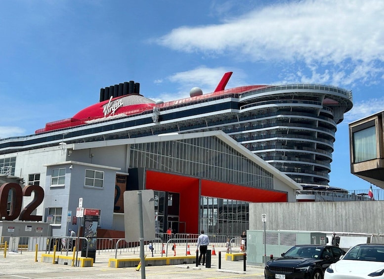 Een cruiseschip ligt aangemeerd in een haven, met een groot bord met het cijfer '02' op de voorgrond. 5