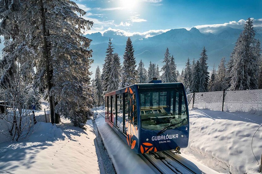 A snow-covered mountain landscape with a cable car labeled 'Gubaltowska' traveling along the tracks. 3