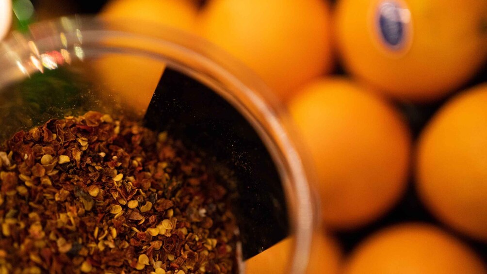 A glass container with a dark interior and a pile of dried herbs or spices. 2