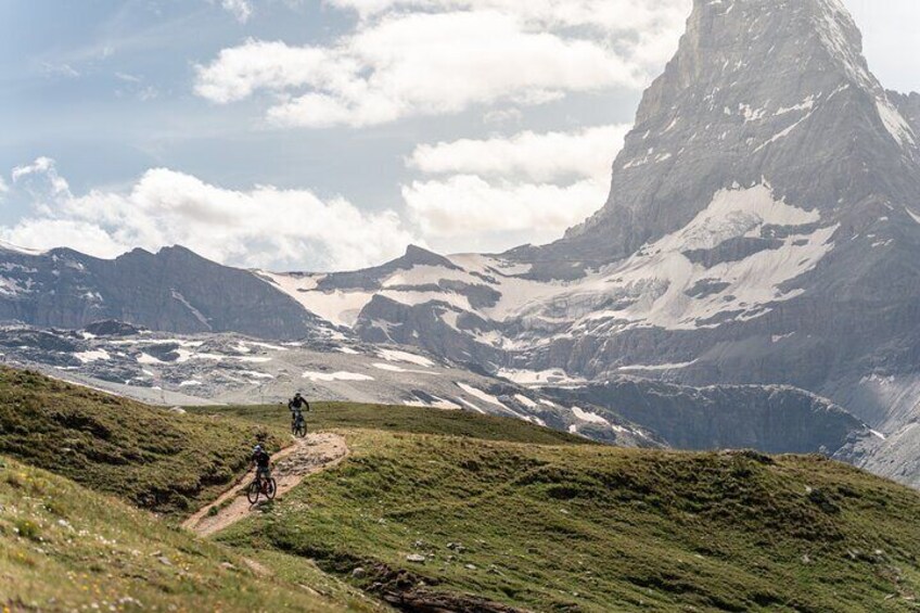 A mountain biking trail with a cyclist and a mountain in the background. 3