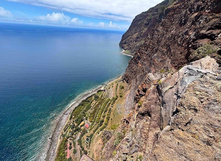 A coastal landscape with a rocky cliff, a beach, and a clear view of the ocean. 5
