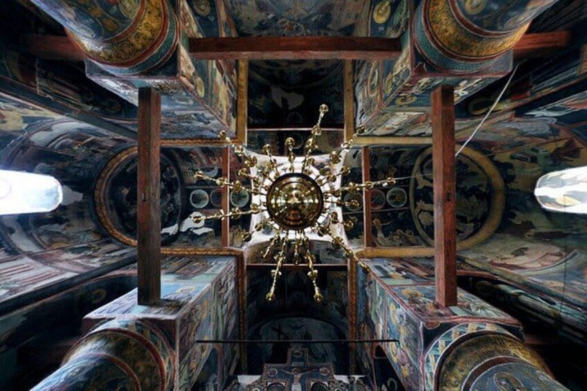 Un interior ricamente decorado con una gran araña central, techo ornamentado y pinturas murales detalladas. 5