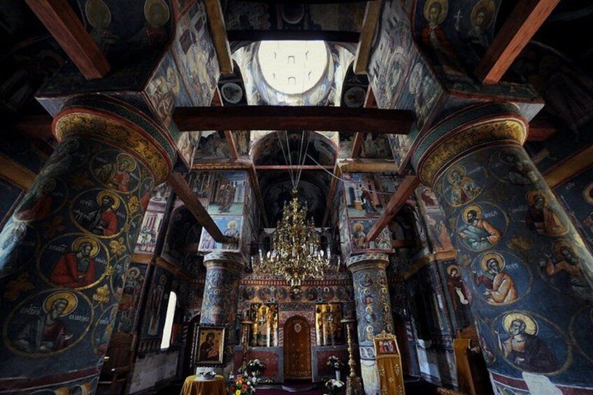 Interior de una iglesia ornamentada con frescos detallados, un altar central y una araña. 4
