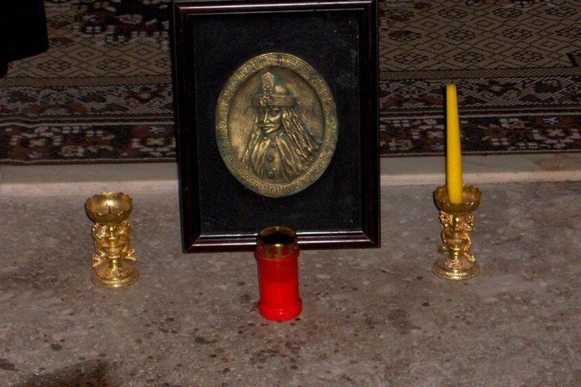 Una estatua de Buda enmarco, una vela roja y dos candelabros dorados sobre un piso de piedra. 2