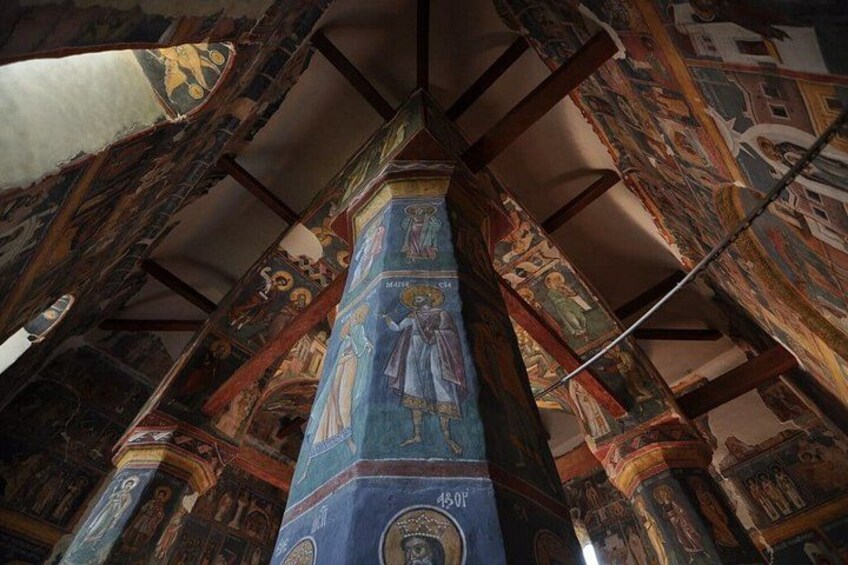 Interior de una catedral con frescos intrincados y un pilar central. 3