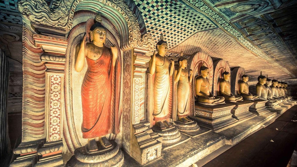 A row of seated Buddha statues in a temple with intricate carvings and a patterned ceiling. 4