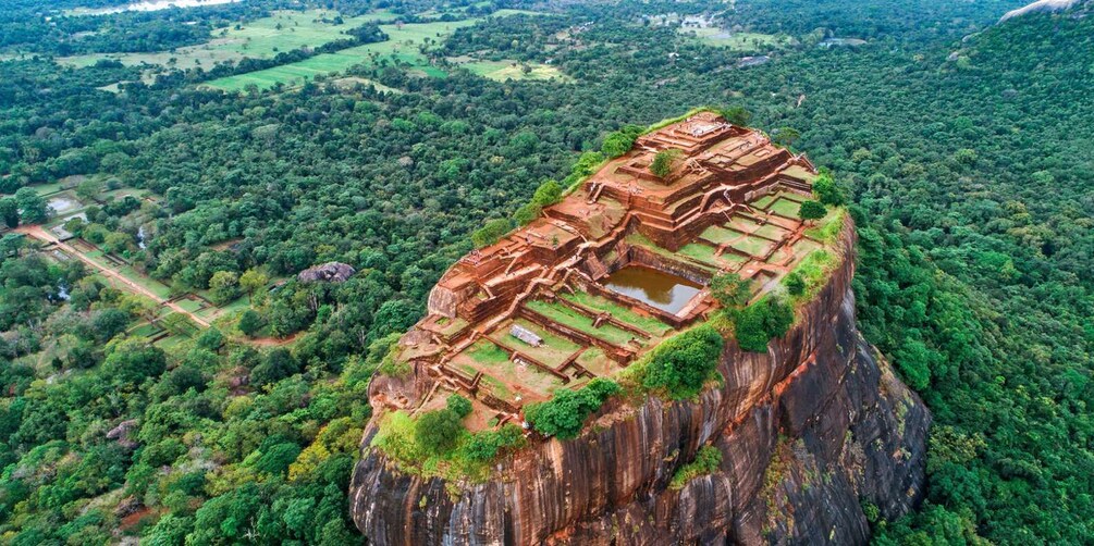 An ancient stone structure perched on a cliff surrounded by dense forest. 1