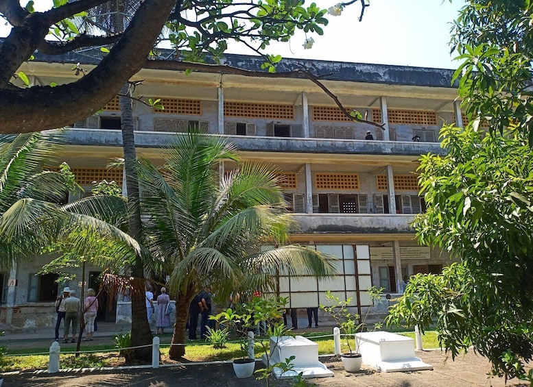 A multi-story building with a courtyard surrounded by palm trees and potted plants. 3