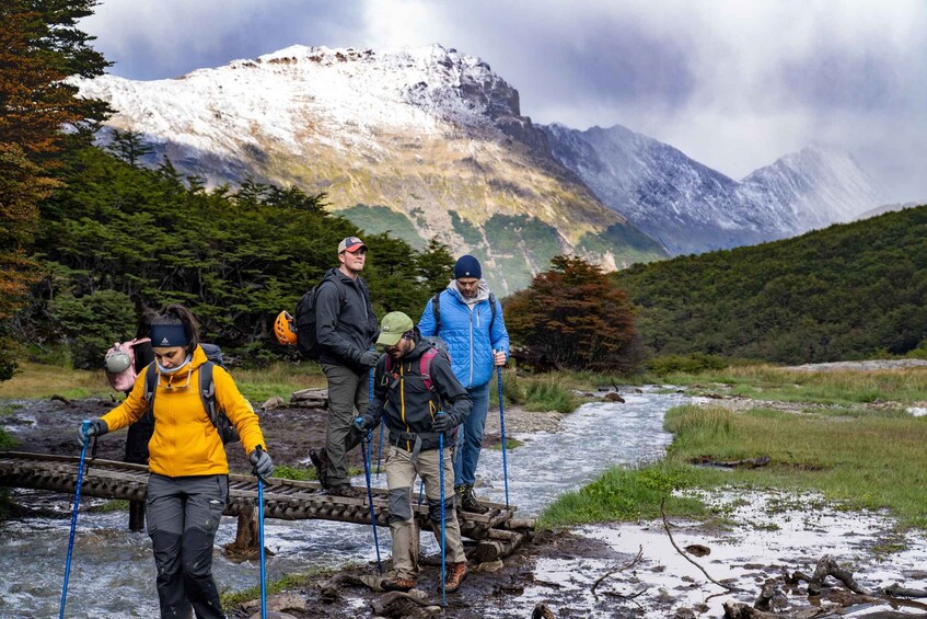 Hikers crossing a river with a mountainous backdrop. 5