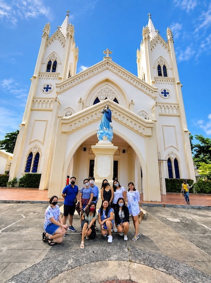 Un grupo de personas posando frente a una catedral con dos torres y una estatua. 1