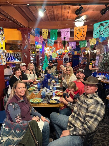 A group of people dining at a restaurant decorated with colorful paper banners. 1
