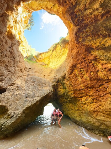 A person standing in a narrow canyon with a large archway. 2