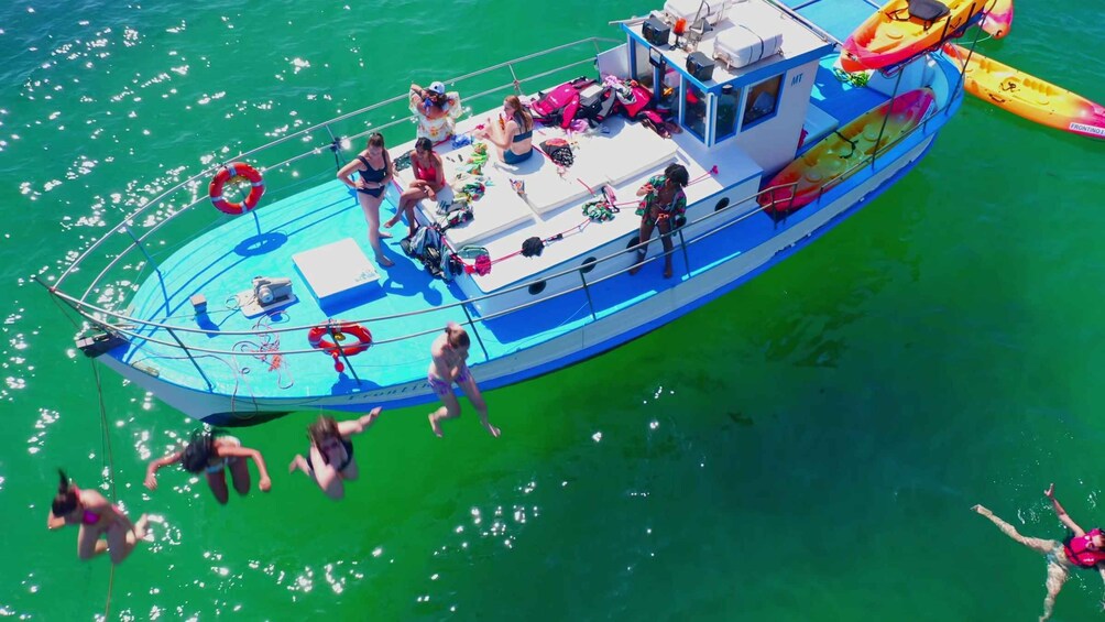 A boat with people on board and some in the water. 1
