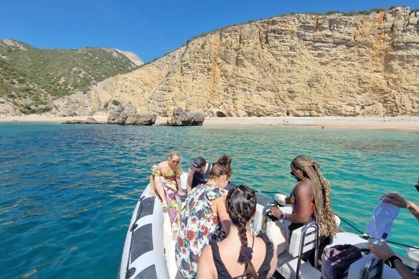 A group of people on a boat in clear waters with a rocky coastline in the background. 2