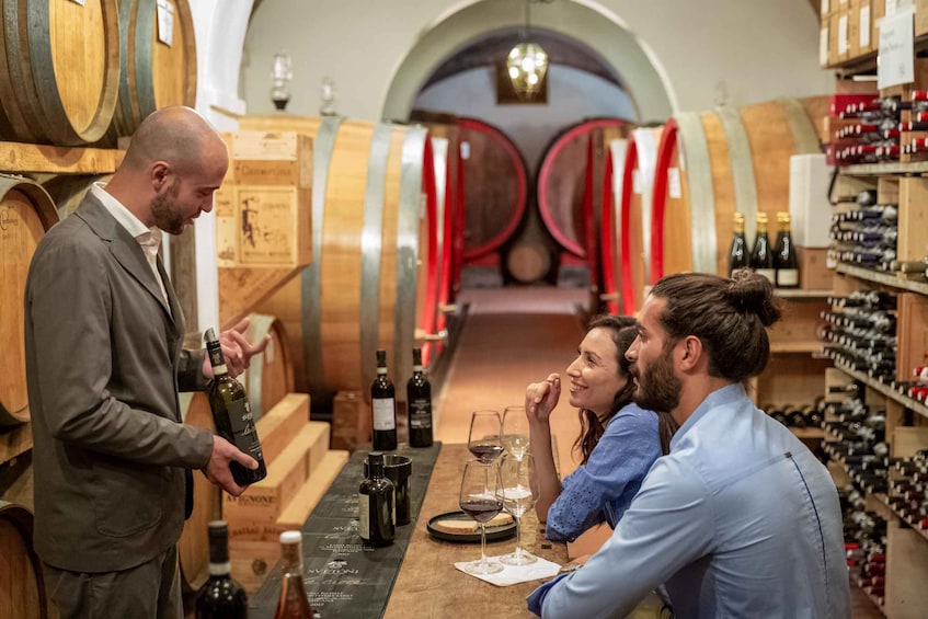 A wine tasting event in a cellar with wooden barrels and wine bottles. 1