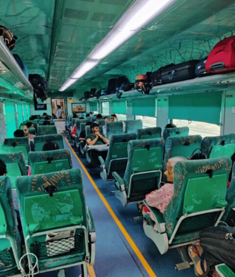 A train interior with rows of seats, some luggage, and overhead luggage racks. 5