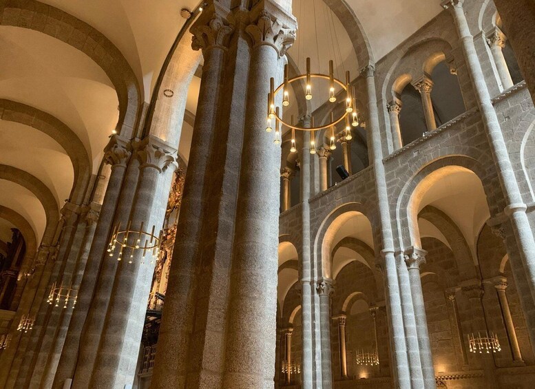 A grand interior with high stone columns and arches, illuminated by chandeliers. 4