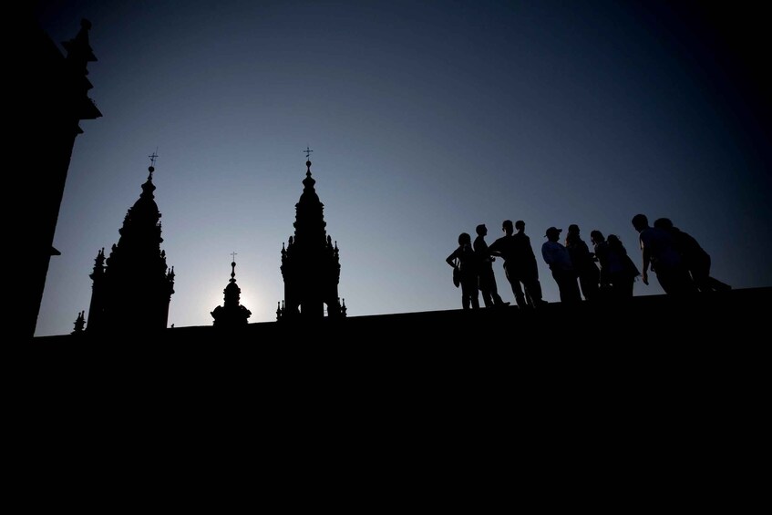 Silhouettes of two spires and a group of people on a hill. 1