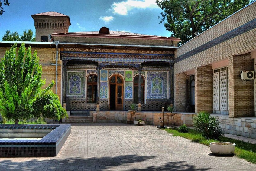 A courtyard with a tiled entrance, a brick building, and a water feature. 4