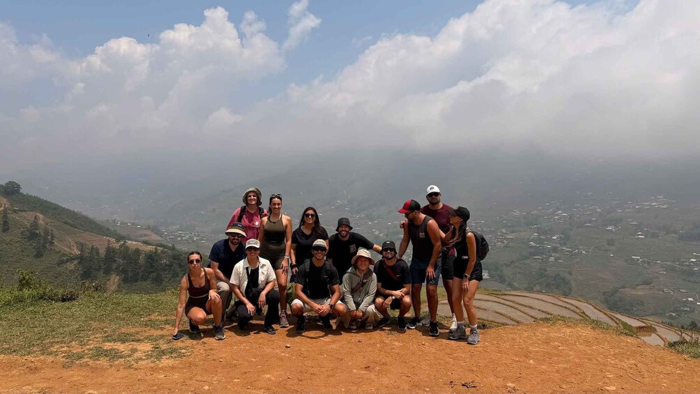 A group of people posing on a hillside with terraced fields in the background. 3