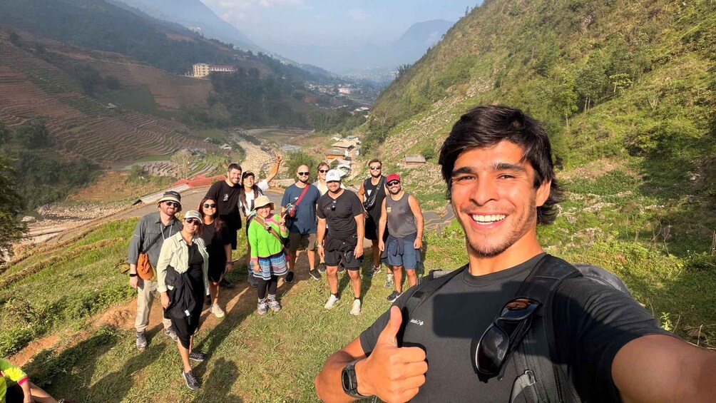 A group of people on a mountain trail with terraced fields and a village in the valley below. 1