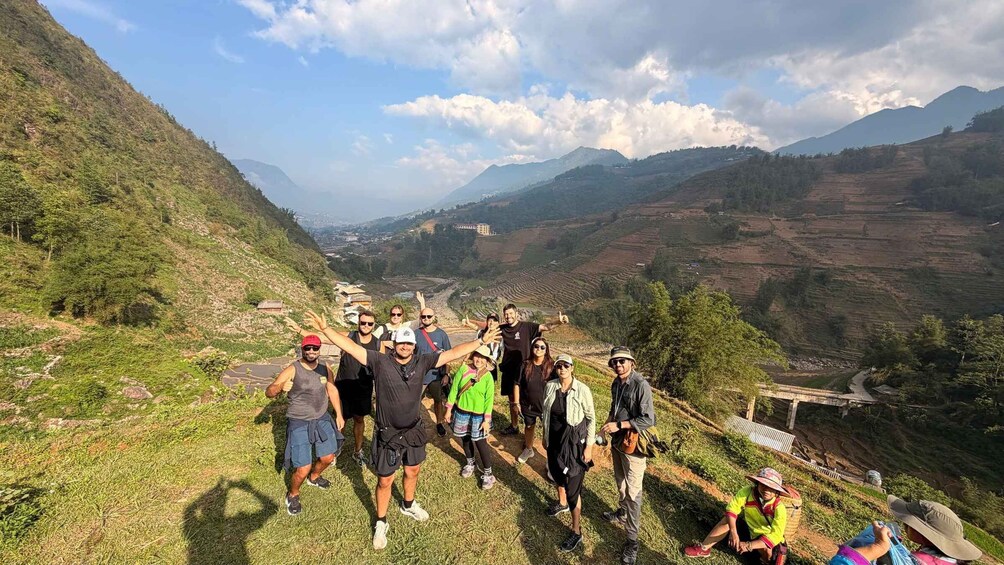 A group of people posing on a hillside with terraced fields and mountains in the background. 5