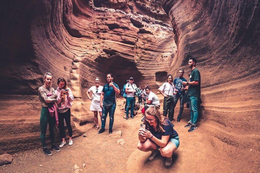 Un gruppo di persone in un canyon stretto con formazioni rocciose stratificate. 1