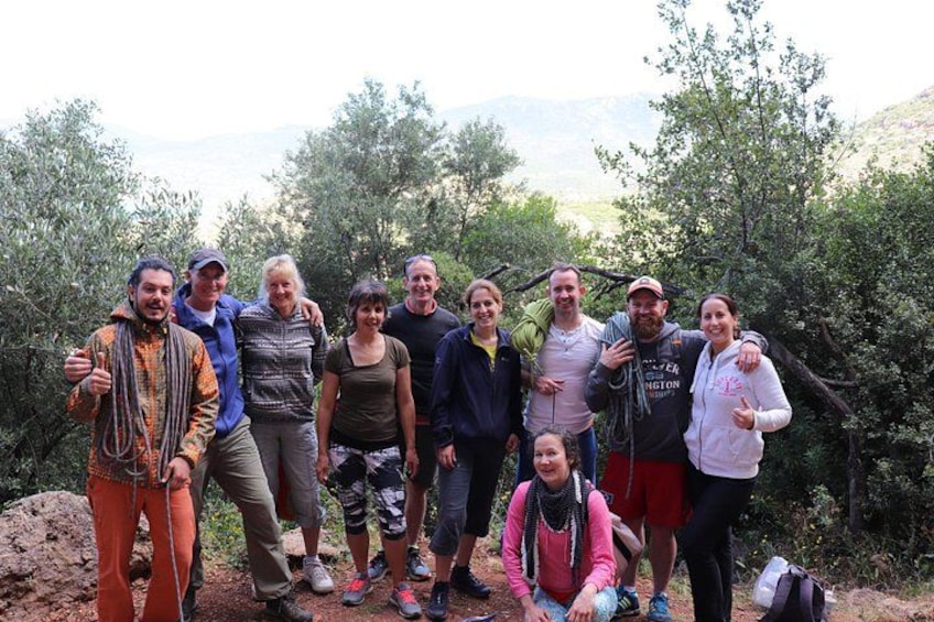 A group of people posing outdoors with trees and mountains in the background. 2