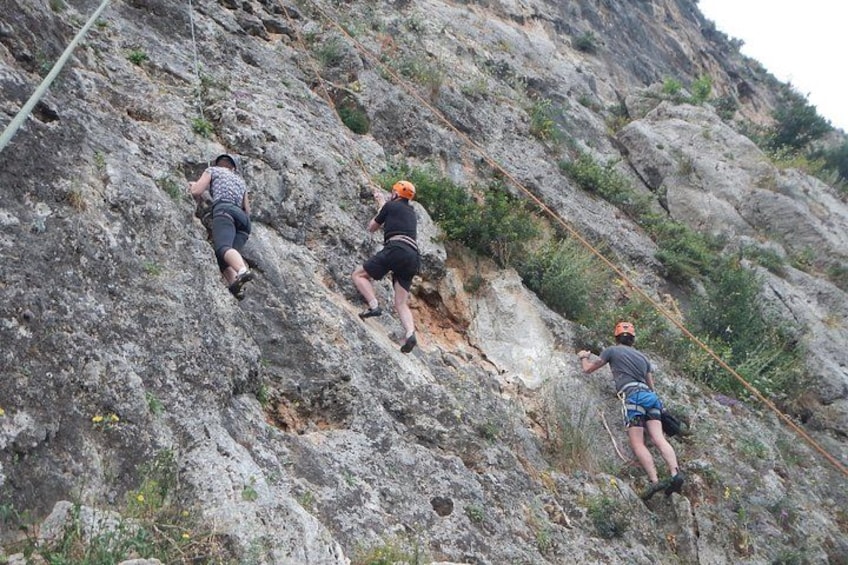 Three people rock climbing on a rocky mountain. 4