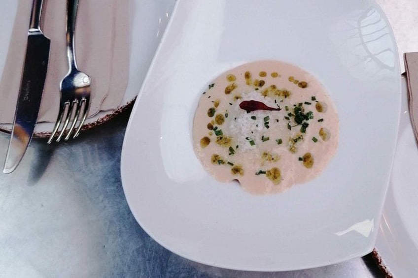 Une assiette blanche contenant un plat crémeux, garni d’herbes et d’un piment. 5