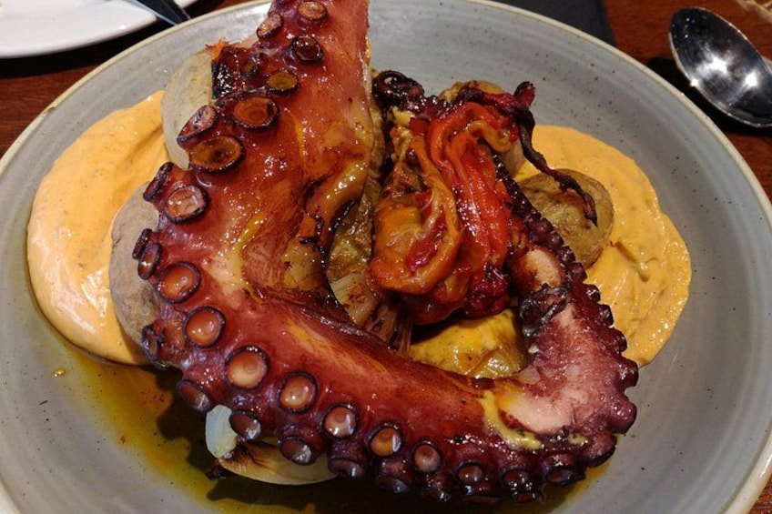 Une assiette de poulpe avec ses tentacules, des pommes de terre et une sauce jaune. 4