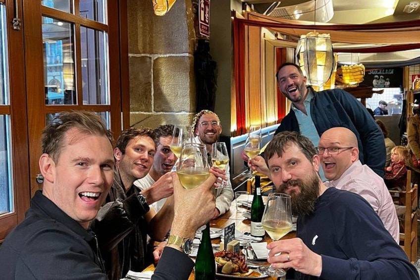 Een groep mensen proost met wijnglazen in een restaurant. 1