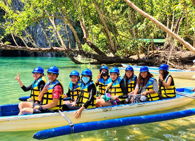 A group of people in a boat wearing life jackets and helmets, surrounded by a calm river and lush greenery. 4