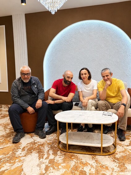 Four people seated on a couch with a marble table in front of them. 3