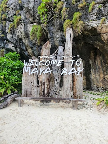 Un letrero de madera con la inscripción 'WELCOME TO MAYA BAY', situado frente a un acantilado rocoso con vegetación. 5