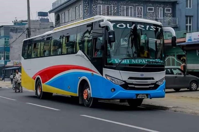 Ein farbenfroher Touristenbus mit dem Schriftzug 'TOURIST' vorne, parkt auf einer Straße. 2
