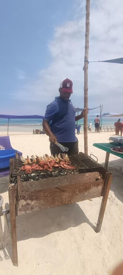 A man grilling seafood on a beach. 2