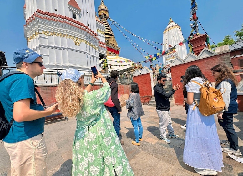 En gruppe mennesker fotograferer foran et tempel pyntet med farverige bedeflag. 2
