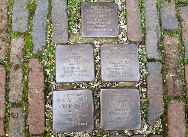 Four stone plaques with names and dates on a brick pavement. 5