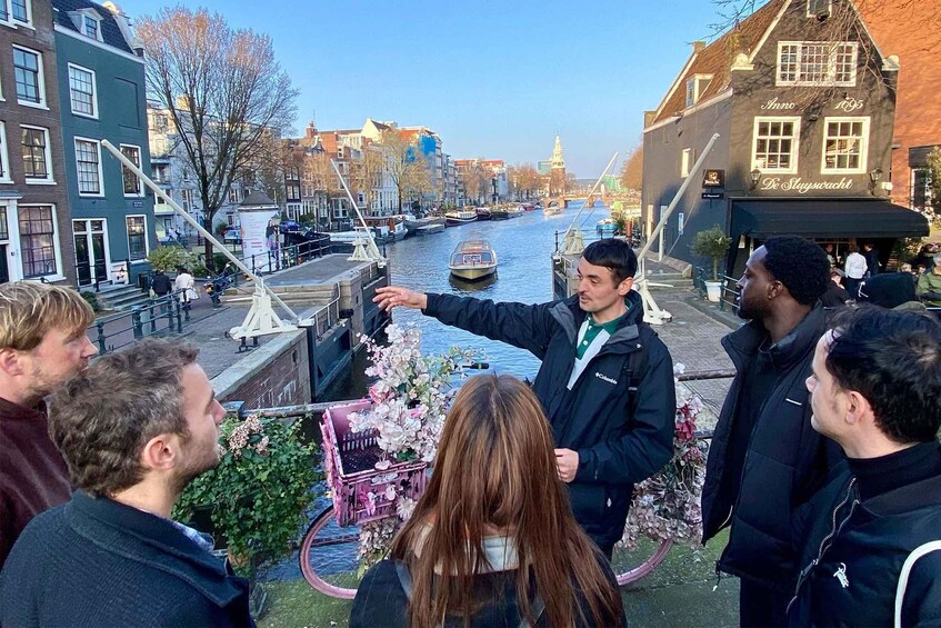 A canal with boats, people standing by the water, and buildings along the canal. 3