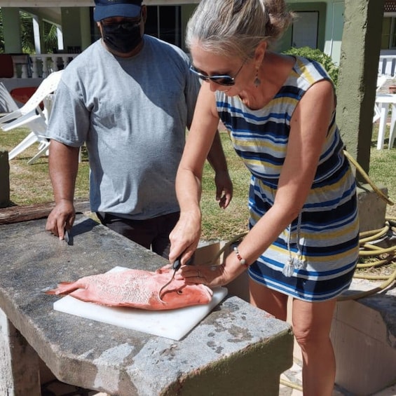 A person cutting a fish on a cutting board. 2