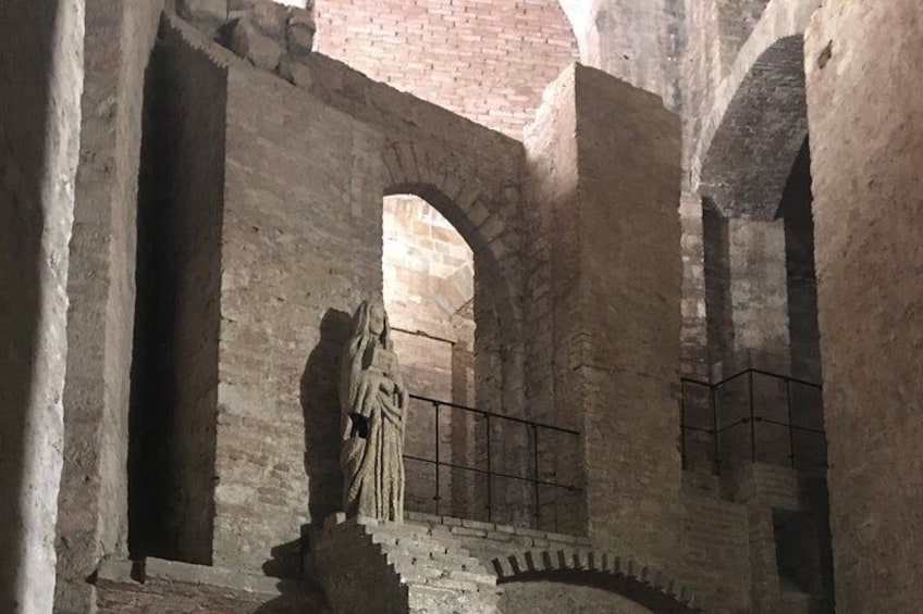 An ancient stone structure with arches and a statue. 4