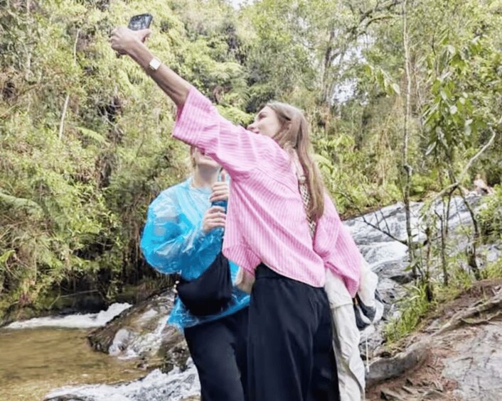 Two people taking a selfie in a forested area with a stream. 2