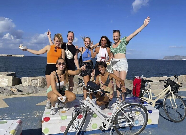 A group of people posing on a colorful platform by the sea with bicycles. 1