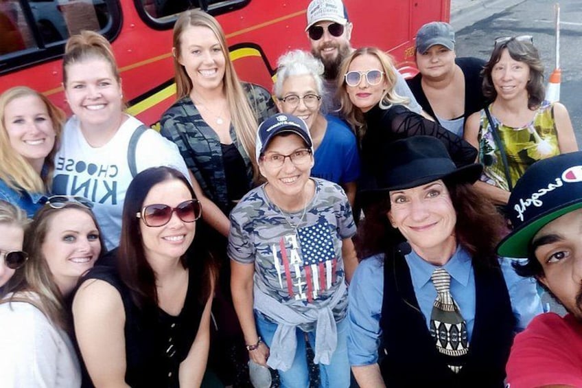 Un grupo de personas posando frente a un autobús rojo con grafitis. 4