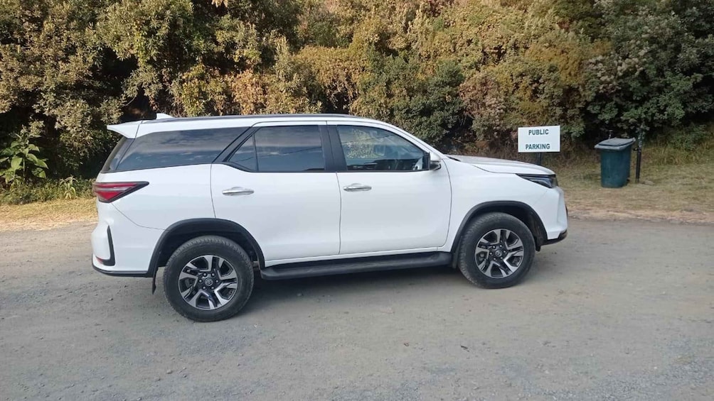 A white SUV parked on a dirt road with a sign indicating public parking. 3