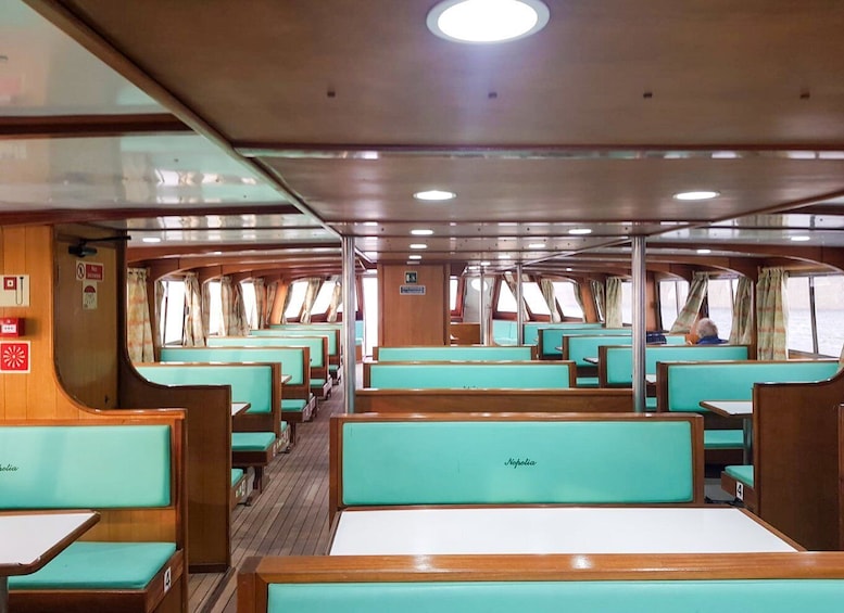 L'intérieur d'un navire de croisière, avec des rangées de sièges turquoise rembourrés et des tables en bois. 5