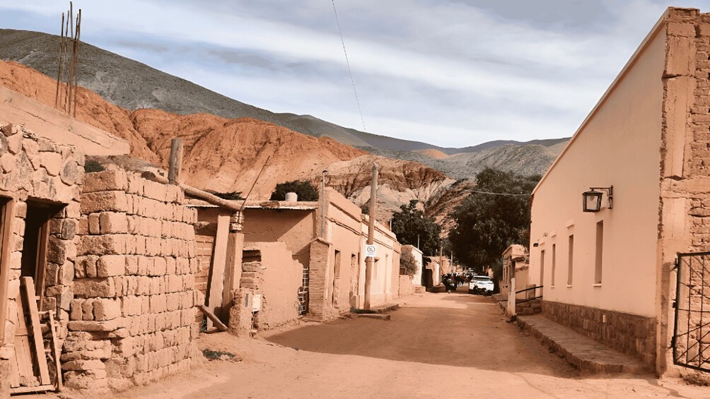 A narrow street flanked by traditional buildings, with a mountain in the background. 2
