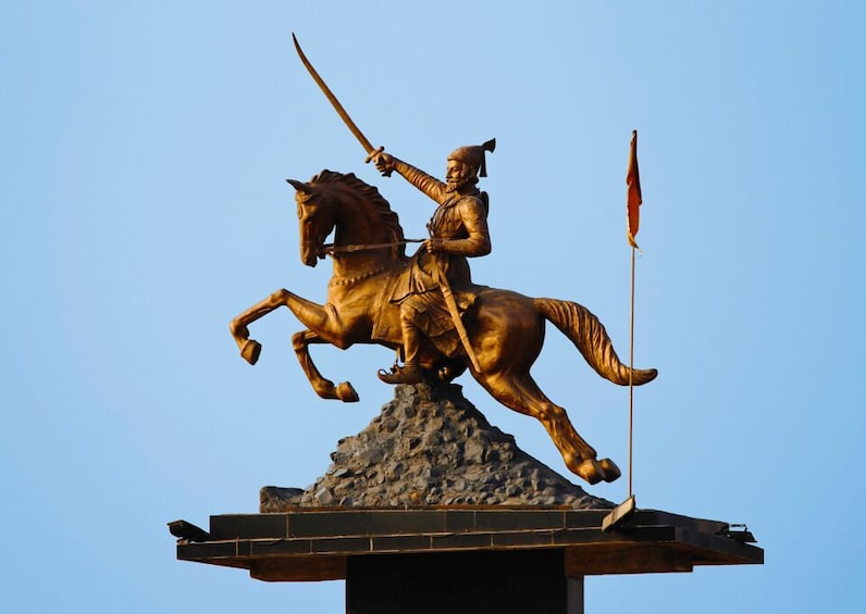 A bronze statue of a mounted figure holding a sword, on a rocky pedestal against a clear sky. 4