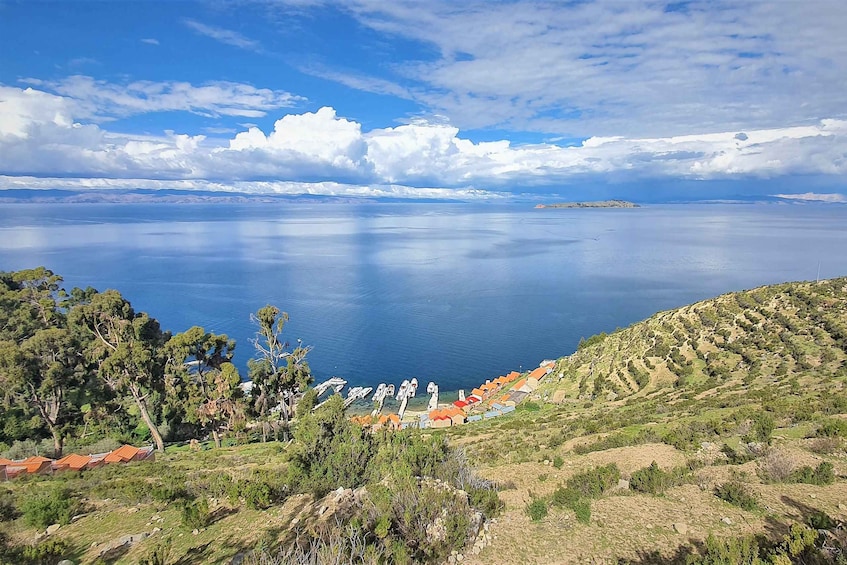 Paesaggio costiero con cielo sereno, mare calmo e un villaggio con case dai tetti arancioni su una collina. 5